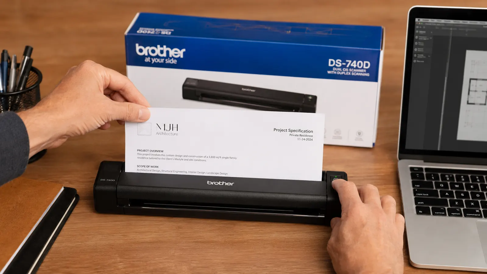 Brother DS-740D scanner on a tidy desk next to a laptop, feeding a document through the slot